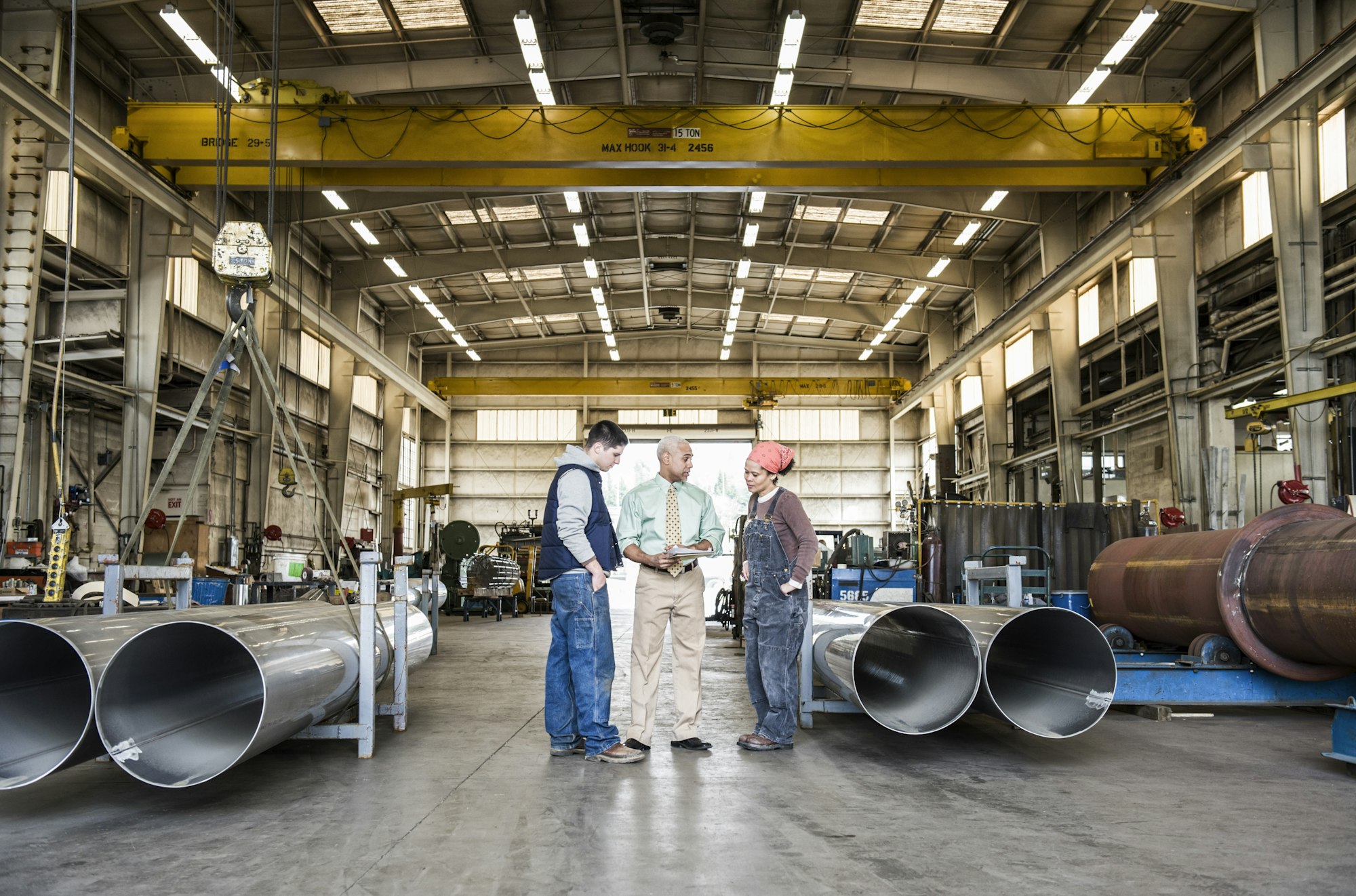 Mixed race team of workers and management people in a large sheet metal factory